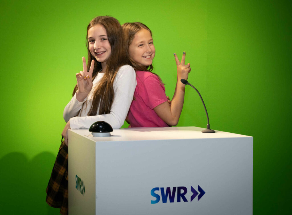 Zwei Mädchen stehen vor einem Green Screen