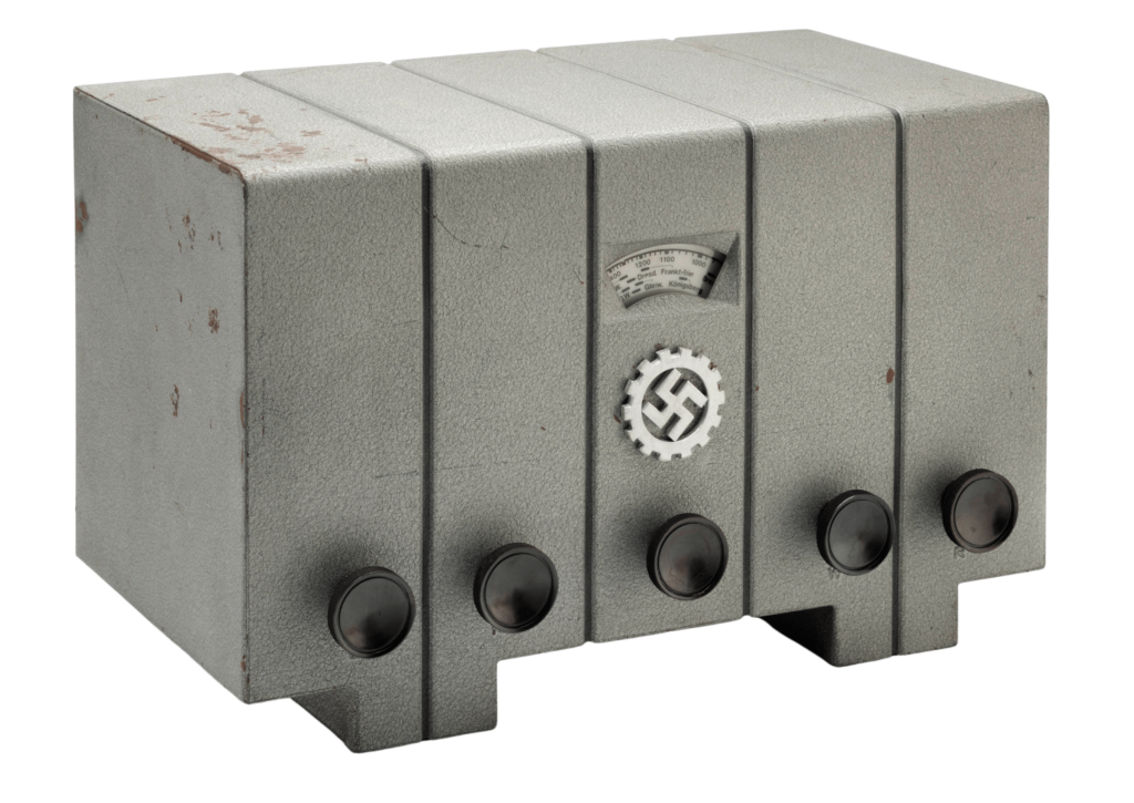 Arbeitsfront-Empfänger „DAF 1011“. Ein grauer rechteckiger Kasten mit fünf Drehknöpfen und Hakenkreuz.